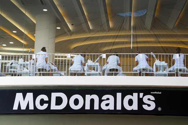 People dressed in white eating on the second floor of a mcdonalds