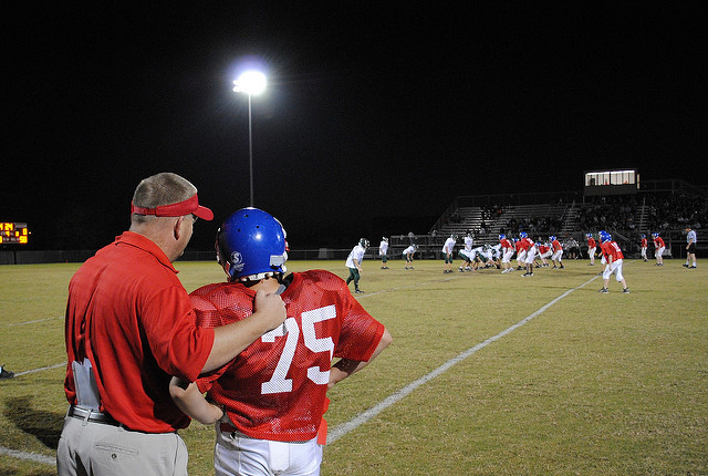 Football Coach talking to player on field